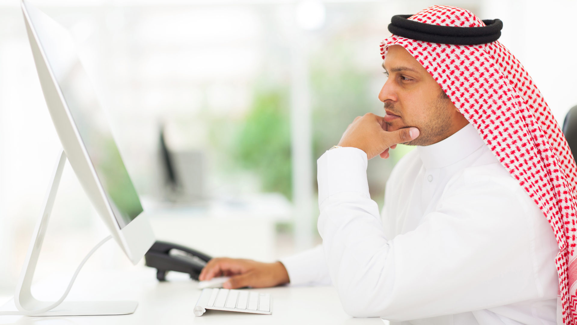 middle eastern businessman looking on a computer screen middle eastern businessman looking on a computer screen, sitting in his office